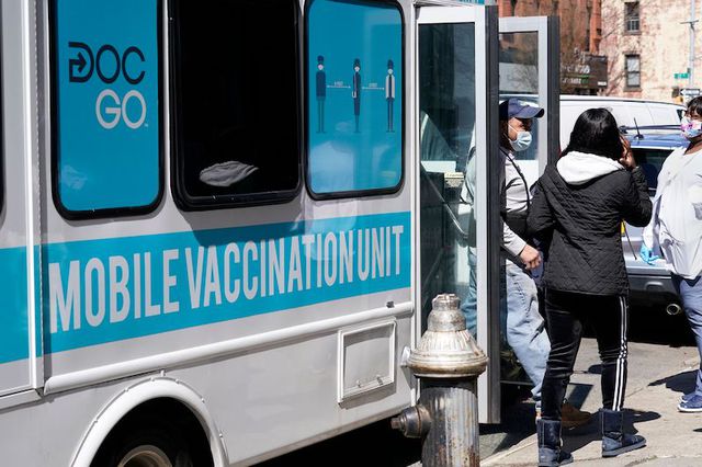 A masked man exits a mobile vaccination van with two staffers standing nearby after receiving a COVID-19 vaccine administered by NYC Test & Trace Corps in partnership with Mixteca, a community organization serving primarily Spanish-speaking and indigenous Latin American populations in the Sunset Park neighborhood of Brooklyn.